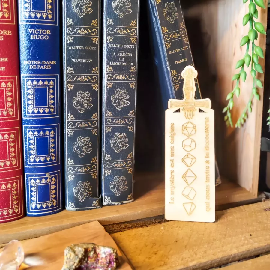 Marque-page en bois gravé en forme de dague, citation « Le mystère est une énigme », dés polyédriques
