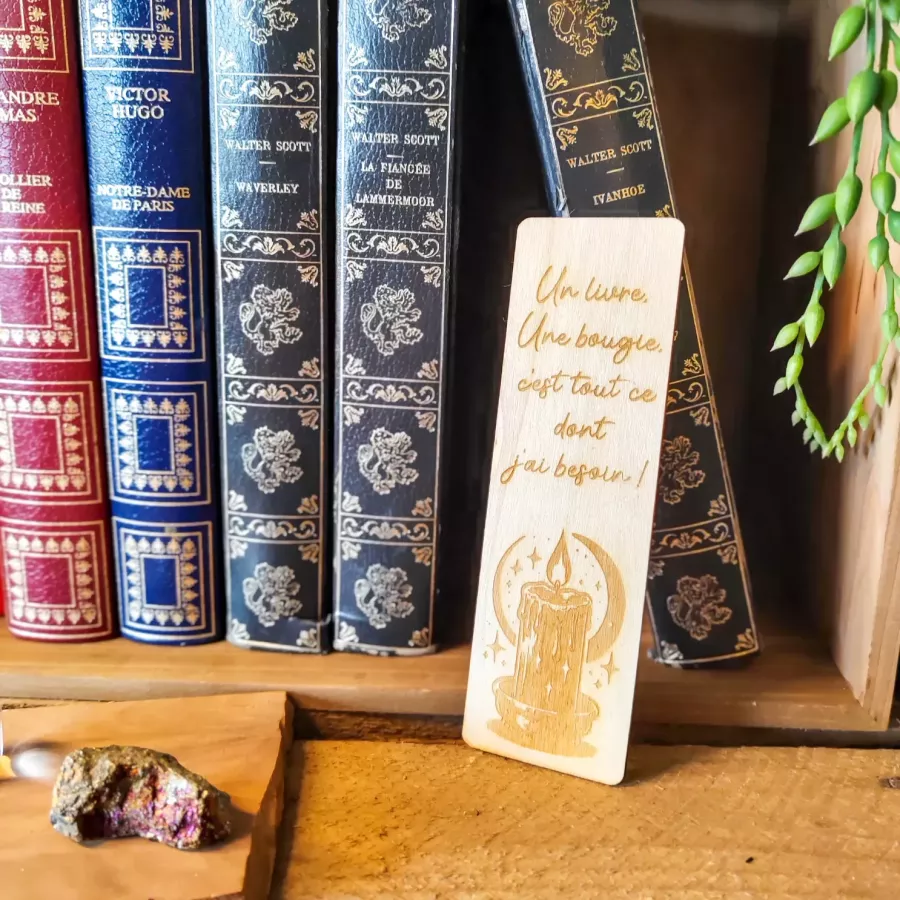 Marque-page en bois gravé avec citation manuscrite « Un livre, une bougie », lune, étoiles et bougie allumée